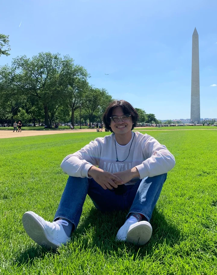 Harviel sitting on the grass on the National Mall